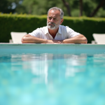 Homme d'âge moyen contemplant la piscine en été